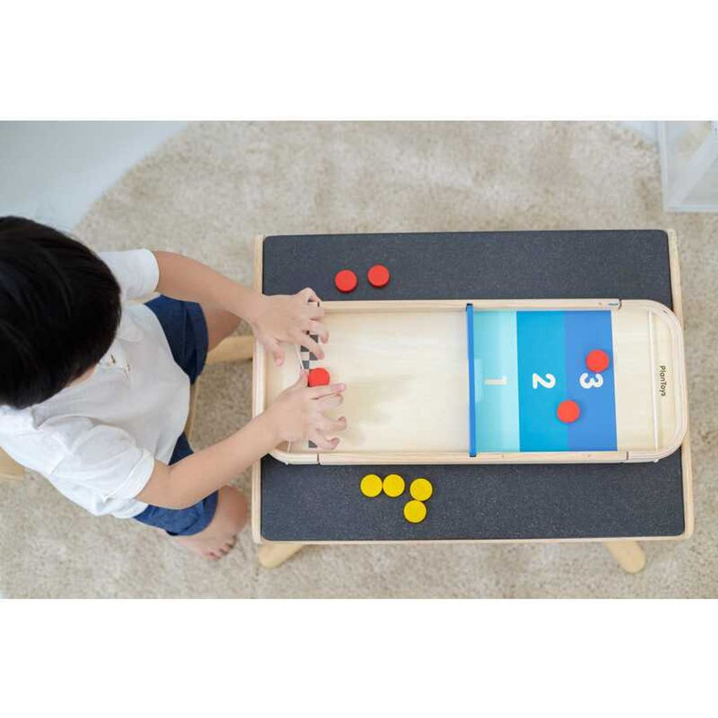 Kid playing PlanToys 2-In-1 Shuffleboard-Game